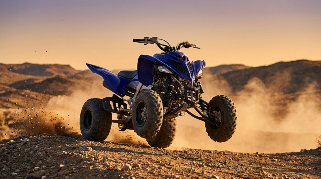 Quad Yamaha Raptor bleu en plein saut sur un terrain désertique, nuage de poussière sous les roues. Coucher de soleil en arrière-plan.
